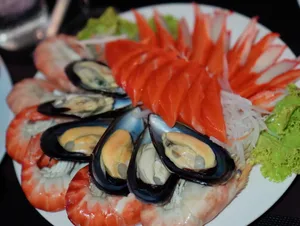 จานซีฟู้ดรวมกุ้ง หอยแมลงภู่ แซลมอน และปูอัด ตกแต่งด้วยผัก