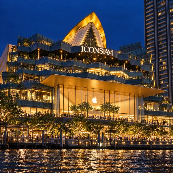 อาคารไอคอนสยามและบริเวณท่าเรือริมแม่น้ำประดับไฟสีทองยามค่ำคืน มีป้าย ICONSIAM และแสงสะท้อนบนผิวน้ำ