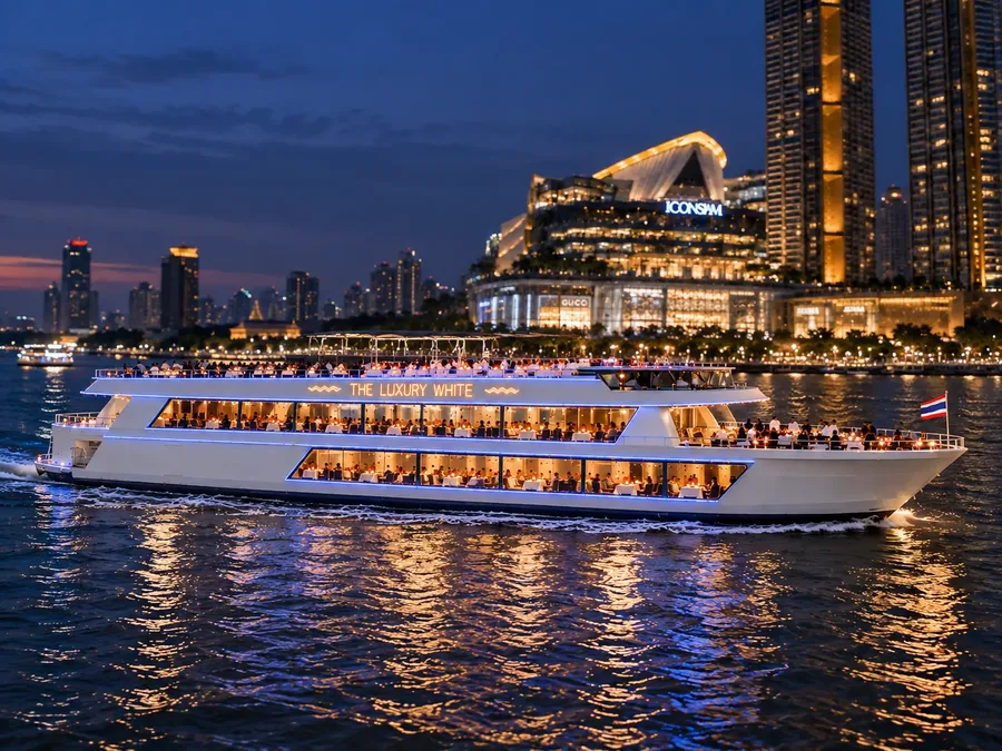 เรือ The Luxury White ล่องบนแม่น้ำเจ้าพระยายามค่ำ โดยมีไอคอนสยามและอาคารริมฝั่งที่เปิดไฟเป็นฉากหลัง