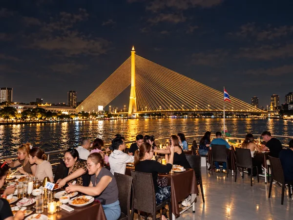 ลูกค้านั่งดินเนอร์บน Unicorn Cruise โซนหัวเรือ-ริม พร้อมชมวิวสะพานพระราม 8 ยามค่ำคืน