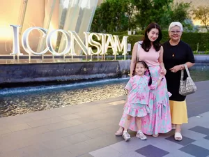 ผู้ใหญ่สองคนและเด็กยืนถ่ายภาพหน้าป้าย ICONSIAM ริมสระน้ำช่วงเย็น