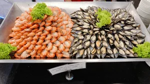 กุ้งและหอยแมลงภู่ครึ่งเปลือกจัดเรียงในถาดบุฟเฟต์บนเรือ Unicorn ตกแต่งด้วยผักสลัด