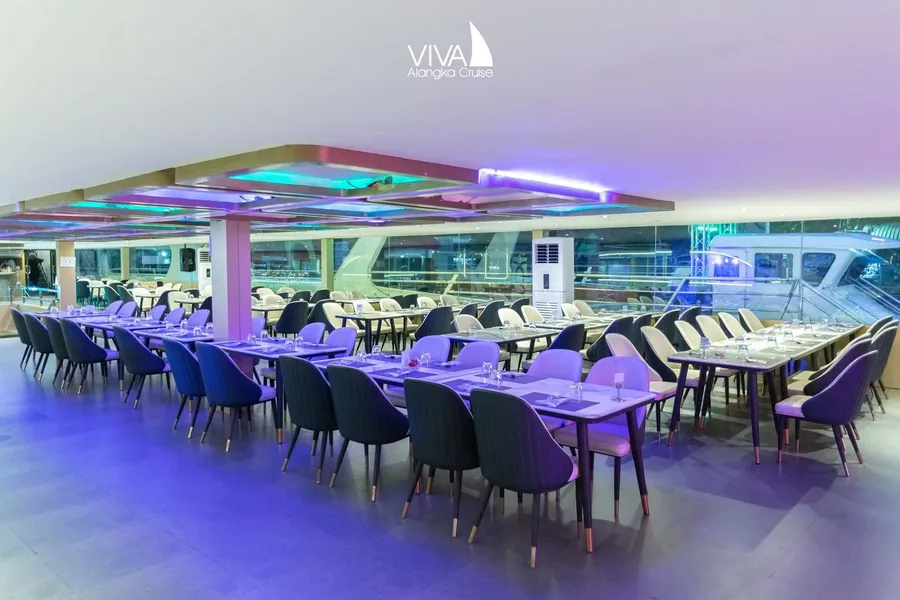 ที่นั่งริมกระจกในห้องอาหารปรับอากาศของ Viva Alangka Cruise พร้อมโต๊ะดินเนอร์และวิวด้านข้างเรือ
