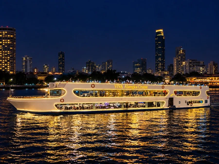 เรือ Viva Alangka Cruise สีขาวประดับไฟสีทองบนแม่น้ำเจ้าพระยา มีอาคารริมแม่น้ำเป็นฉากหลังยามค่ำคืน