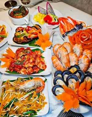 อาหารหลายจานบนโต๊ะ มีทั้งกุ้ง หอยแมลงภู่ แซลมอน ปูอัด ผัดไทย และผลไม้ ในชุดภาพรีวิวเรือ Viva Alangka Cruise