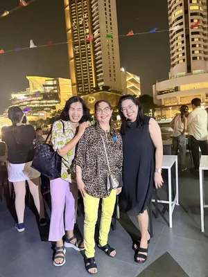 ผู้โดยสารหญิงสามคนถ่ายภาพบนเรือ Viva Alangka Cruise โดยมีไอคอนสยามและอาคารประดับไฟเป็นฉากหลัง