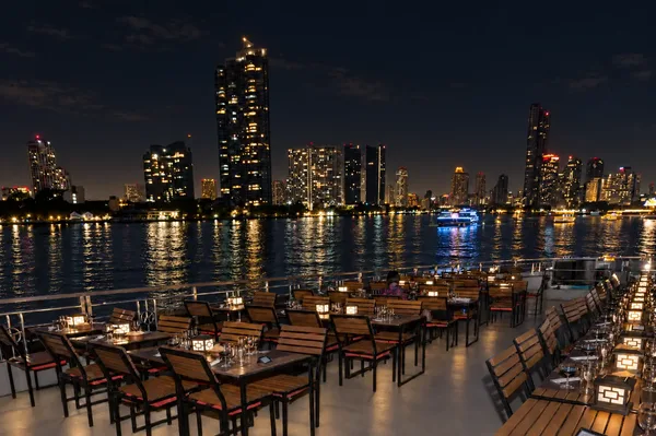 โซนที่นั่งริมดาดฟ้าเรือ White Orchid River Cruise รอบ Dinner มองเห็นเส้นขอบฟ้ากรุงเทพฯ และแสงสะท้อนบนแม่น้ำเจ้าพระยา